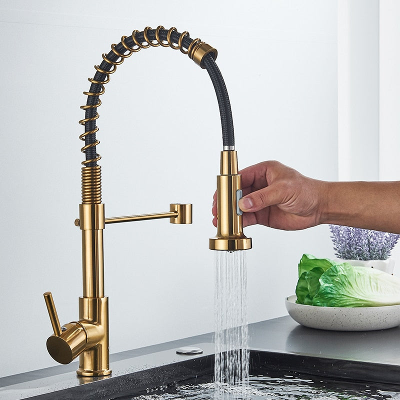 A hand uses the Quyanre Pro Spring Neck Pull-Down Kitchen Faucet’s flexible, coiled spray head to rinse vegetables in the sink, while lettuce and other greens sit on a nearby plate.