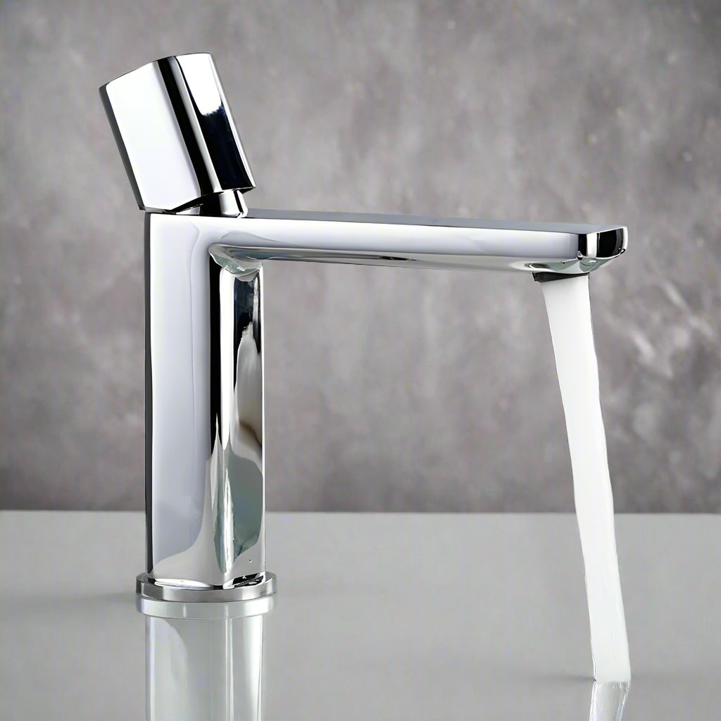 The Morsale.com Polished Chrome Bathroom Sink Faucet – Single Handle features a sleek design and reliable ceramic valve, delivering a steady stream of water onto a glossy white surface with a blurred gray background.