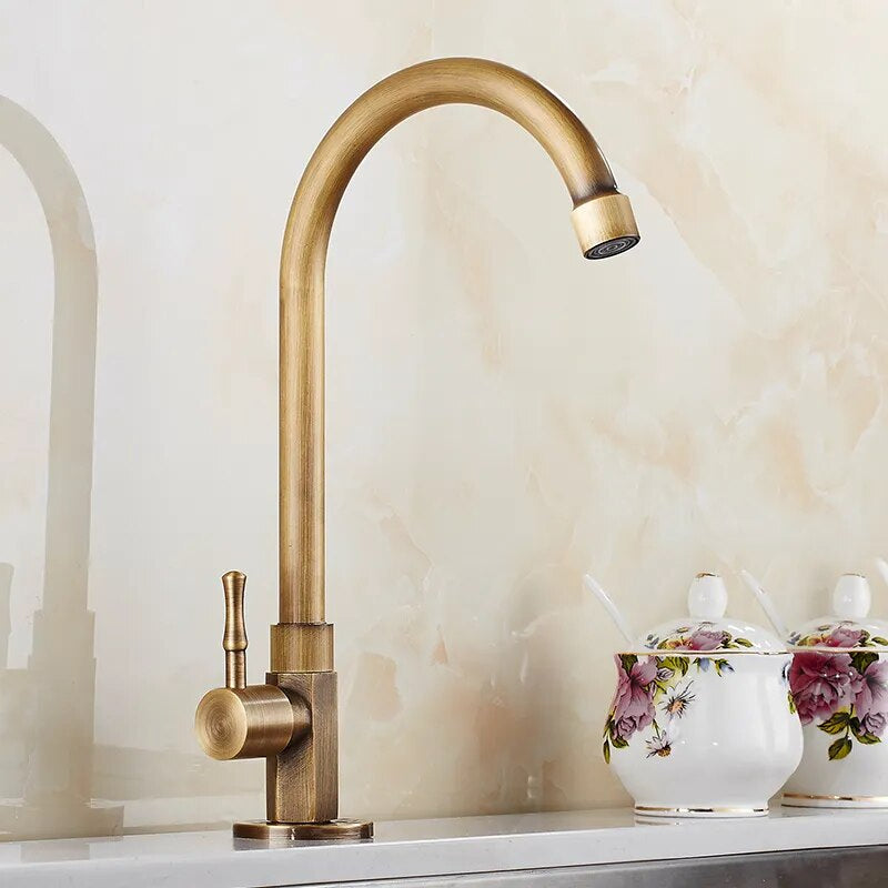 The ZGRK Antique Brass Single-Handle Kitchen Faucet with a curved spout is installed on a countertop, while floral-patterned ceramic containers with lids and spoons in the background add charm.