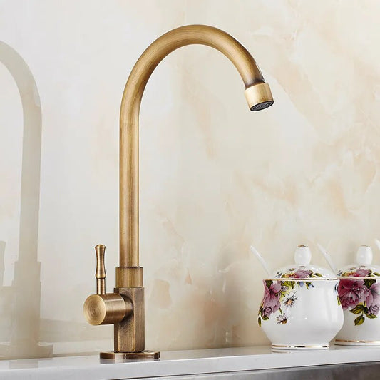 The ZGRK Antique Brass Single-Handle Kitchen Faucet with a curved spout is installed on a countertop, while floral-patterned ceramic containers with lids and spoons in the background add charm.