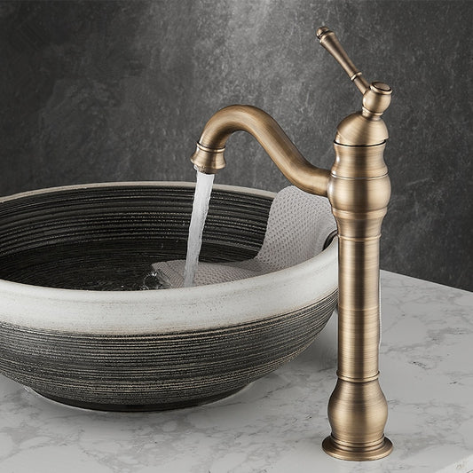 The Maison Single Handle Bathroom Faucet by Tiqui pours into a round, black and white patterned ceramic sink on a white marble countertop, set against a dark stone background.