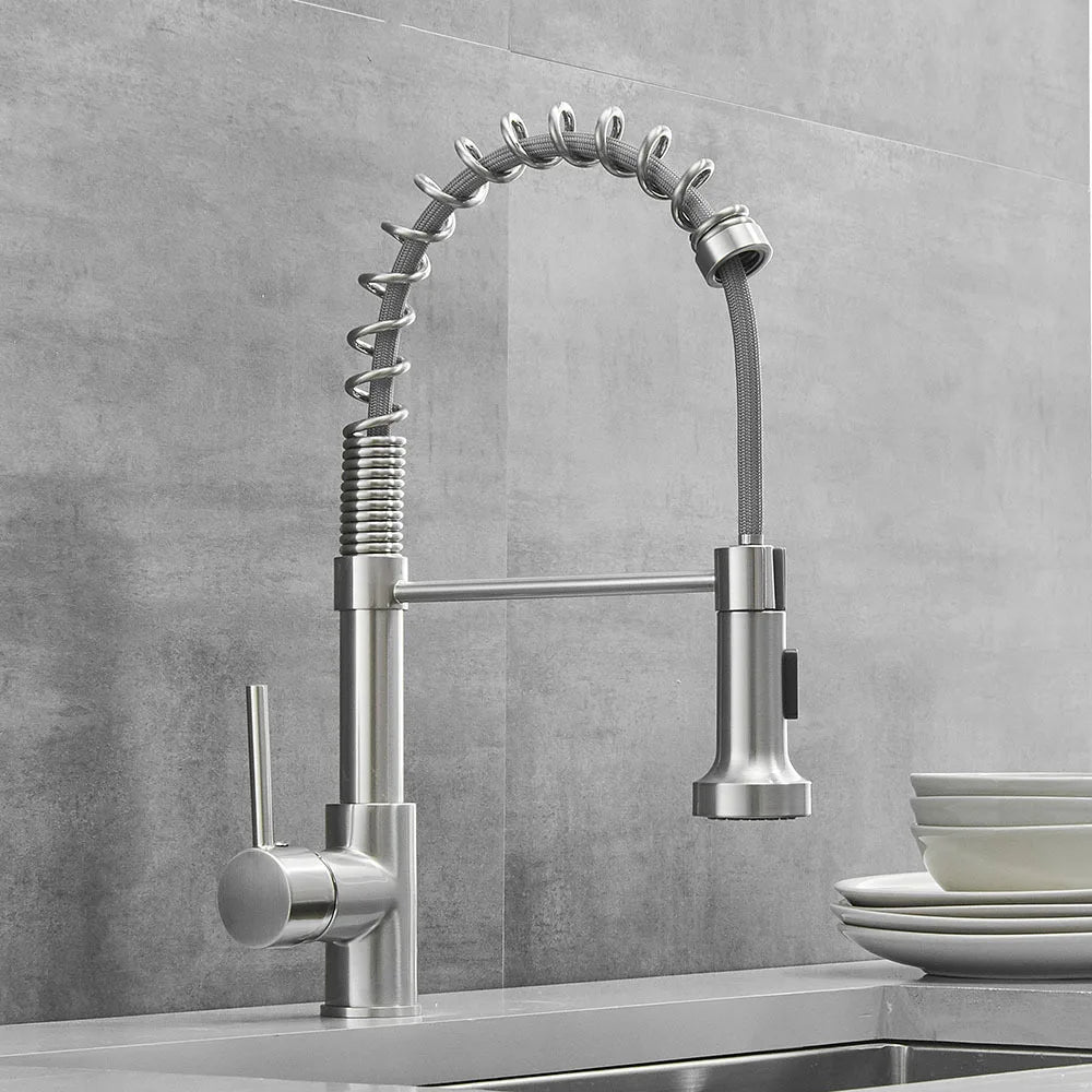 The Smesiteli Modern Pull-Down Spring Kitchen Faucet features a flexible coiled design, single lever handle, and pull-down spray head. Solid brass construction is showcased above the sink, with stacked white dishes to the right.