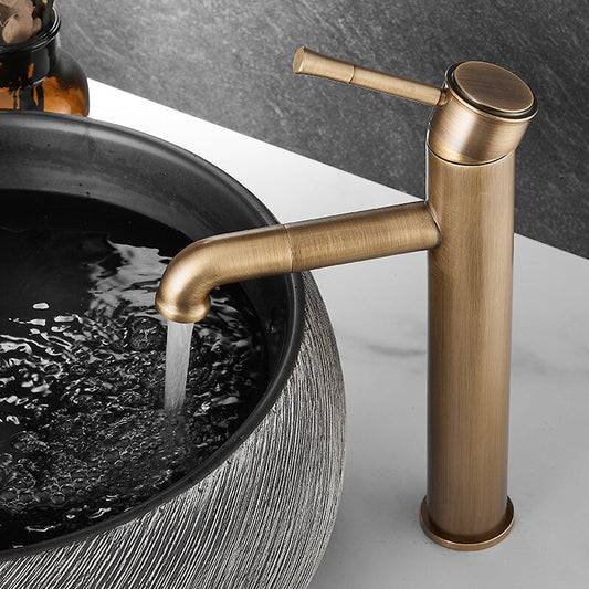 The Tiqui Maison Antique Bronze Bathroom Faucet dispenses water into a round, textured gray vessel sink on a white countertop set against a dark backsplash.