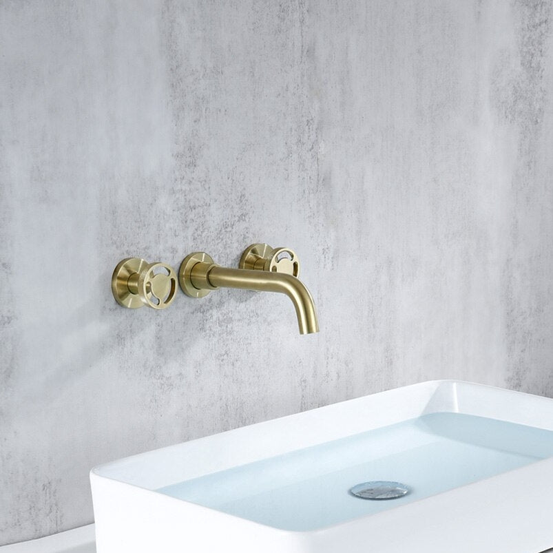 A white basin filled with water features the Morsale.com Dual-Handle Wall-Mount Brass Faucet in gold, set against a light gray textured wall for a modern bathroom look.