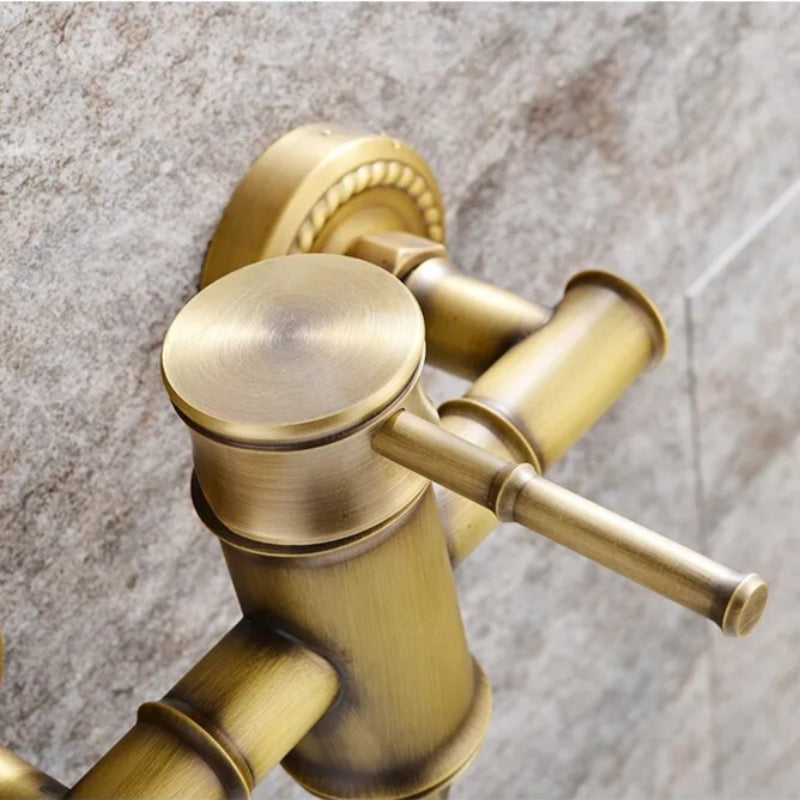 Close-up of the Ellen Antique Brass Shower & Tub Faucet System, featuring a vintage-inspired brushed gold finish and single lever handle, mounted on a textured stone or tile wall.