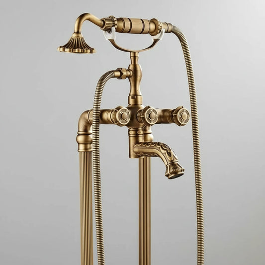 The Allfixture Heritage Floor-Mounted Bathtub Filler & Hand Shower Faucet, featuring ornate handles and two flexible hoses, stands elegantly against a plain light gray background.
