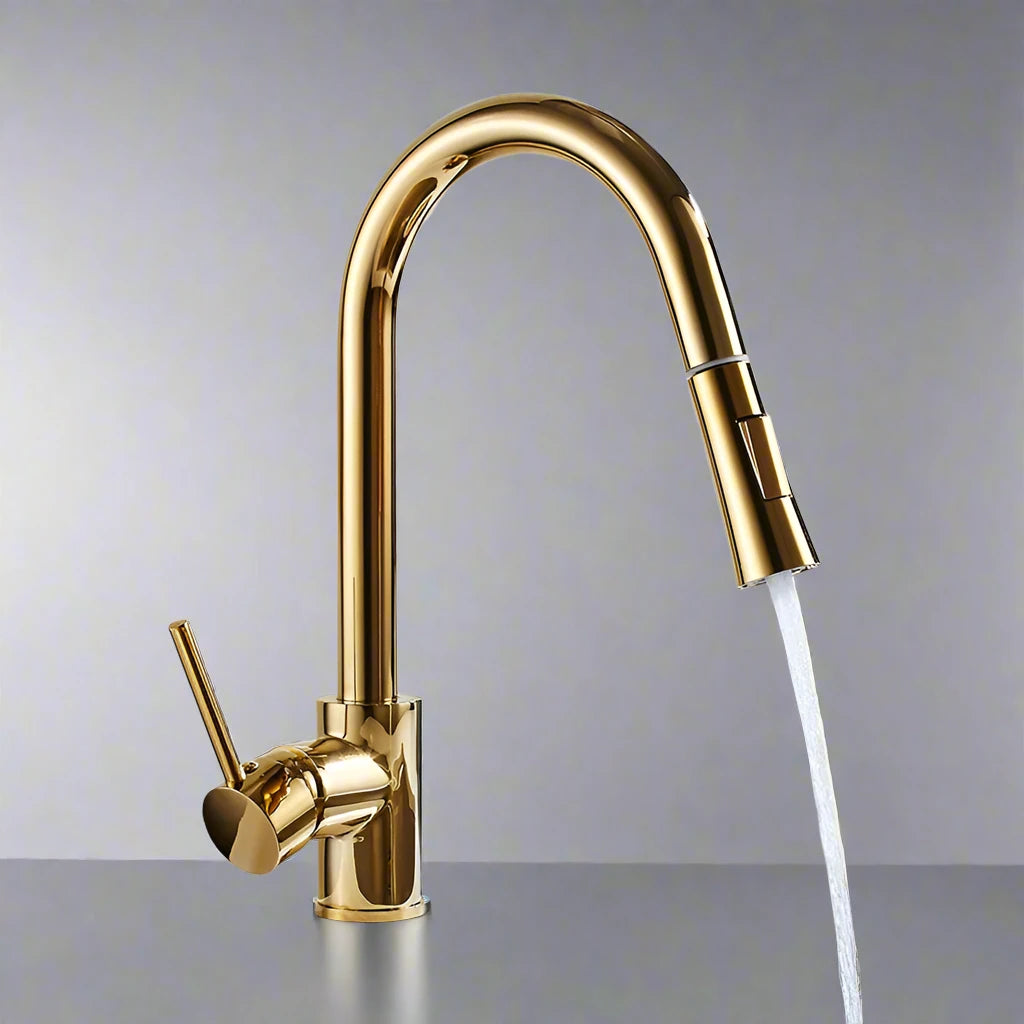 A hand holding the detachable spray head of Tiqui's Single Handle Pull Out Kitchen Faucet, directing the water stream into a stainless steel sink. The sleek, gold-colored faucet features a single lever handle for controlling water flow and temperature. The background shows a marble-like wall.
