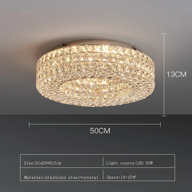 The Bacci Crystal Ceiling Light Fixture by Morsale, featuring LED bulbs, is elegantly installed on the ceiling, casting a warm glow. The illumination dances off the crystals, producing a sparkling effect. The room boasts modern decor with dark walls and offers a view of the dining area below.