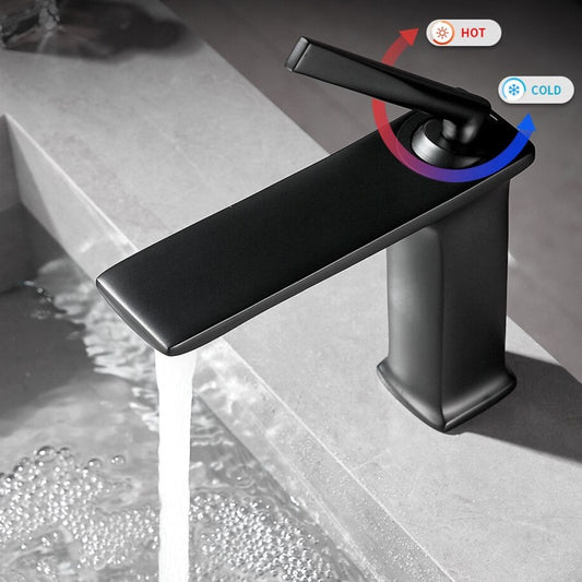 The Wanfan Valmont Single-Handle Bathroom Faucet pours water into a sink on a gray countertop. Above the handle, an arrow shows red for hot and blue for cold, blending modern style with functional design.