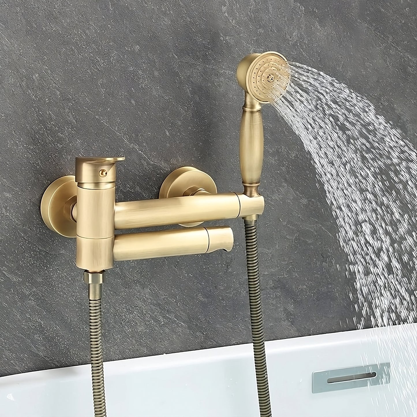 The Tiqui Antique Brass Handheld Shower Head With Bathtub Faucet is a modern, wall-mounted set installed against a textured, dark gray wall above a white bathtub. It features a handheld showerhead with water streaming out and a sleek bathtub faucet.