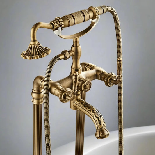 The Allfixture Heritage Floor-Mounted Bathtub Filler & Hand Shower Faucet features vintage-inspired design, two handles, a curved spout, and a handheld shower with a floral-shaped nozzle in an antique brass finish.