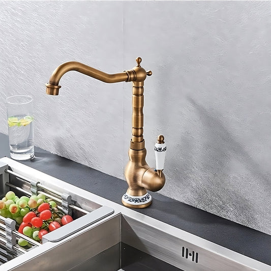 The Ellen Heritage Single-Handle Kitchen Faucet in vintage-style brass with a white and blue ceramic handle is mounted beside a modern stainless steel sink filled with vegetables, near a glass of lemon-mint water.
