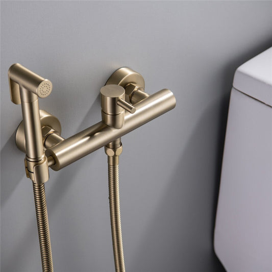 The allfixture Windsor Wall-Mounted Bidet Faucet, in a modern gold finish with flexible hoses and cylindrical handles, is installed on a light gray wall beside a white toilet for a stylish look.