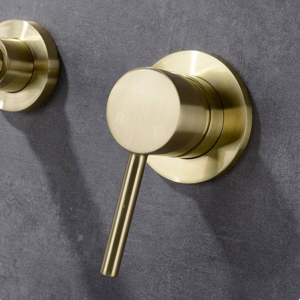 A modern Wall Mounted Solid Brass Bathroom Faucet from Morsale.com is shown pouring water into a white sink. The bathroom faucet features a sleek, curved spout and a single handle for temperature control. The background is a light gray wall with a small plant partially visible.