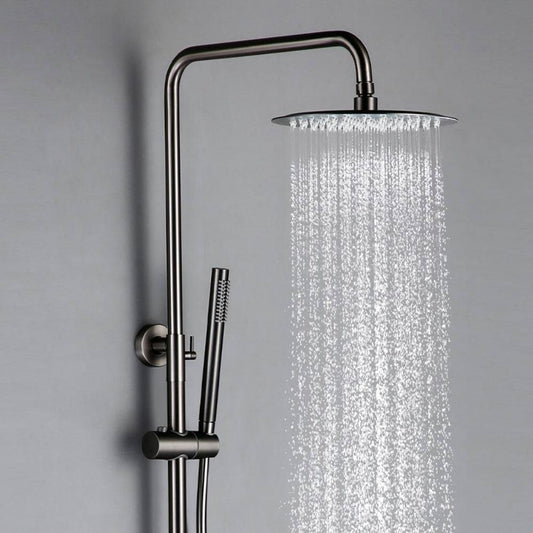 The Wasser™ Gunmetal Complete Shower System from Morsale.com features a sleek, modern design with a stainless steel rain shower head and a handheld attachment. Water flows from the round, flat shower head, creating a smooth cascade of droplets against a plain grey background.