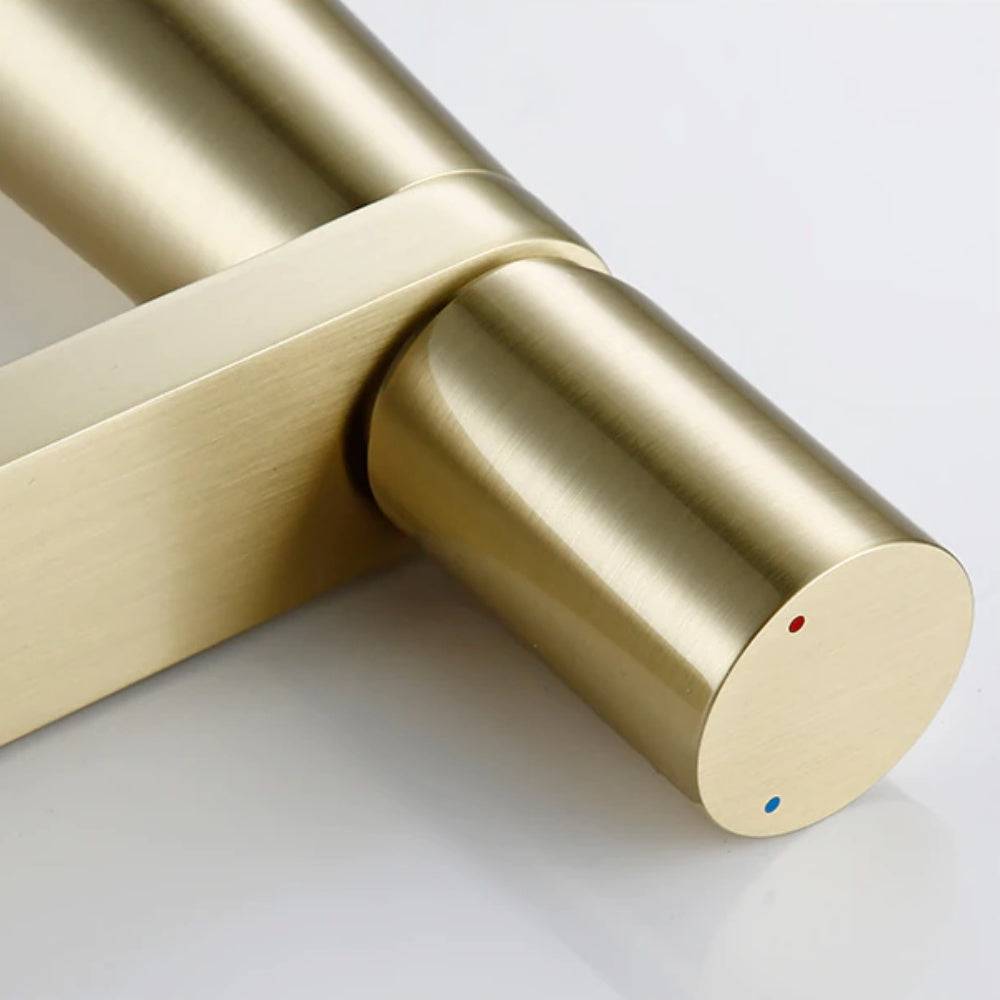A close-up view of the contemporary Wasser™ Solid Brass Single Handle Bathroom Sink Faucet from Morsale.com, showcasing its sleek cylindrical handle. The handle has two small dots: one blue for cold water and one red for hot water. The background features a light blue wall, with a white surface underneath the faucet.