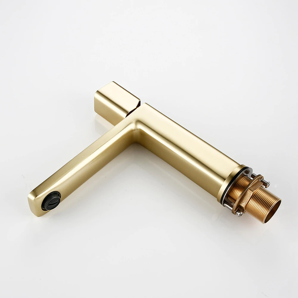 A sleek, modern Wasser™ Solid Brass Bathroom Sink Faucet from Morsale.com pours water into a rectangular white sink. The water flows smoothly, creating ripples in the filled basin. The background includes a gray wall and a corner of a wooden tray on the countertop.