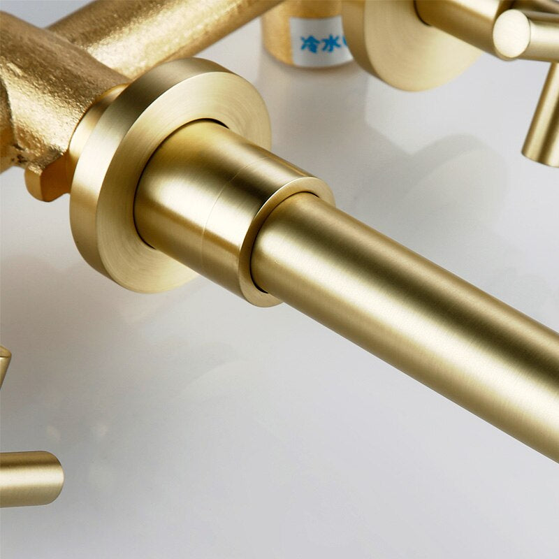 The Wasser™ Solid Brass Wall Mounted Bathroom Faucet from Morsale.com is a modern bathroom sink accessory with a matte gold finish. It features a sleek, curved spout and cross handles for hot and cold water. Clear water flows from the spout into the white sink below, adding an elegant touch to your bathroom decor.