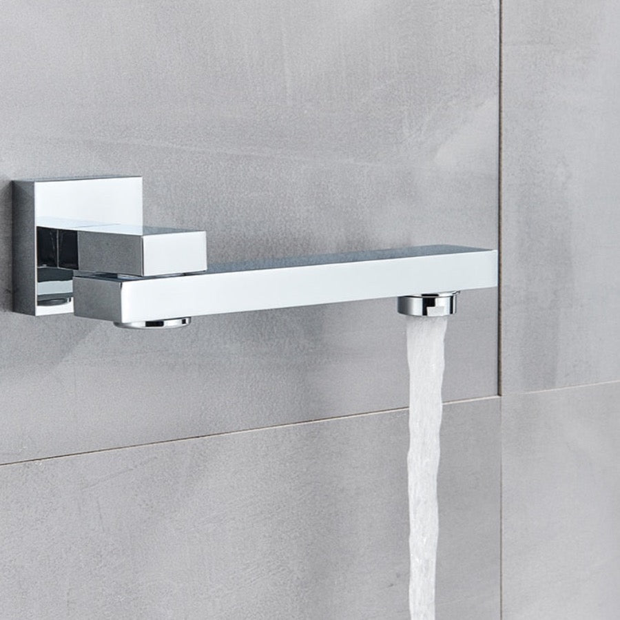 An AllFixture Wall Mount Swivel Spout Wash Basin Bathroom Faucet, featuring a modern, chrome-plated design with minimalist elements, pours a steady stream of water against a light gray tiled wall. The faucet has a sleek, rectangular form that enhances the contemporary aesthetic of the bathroom setting.