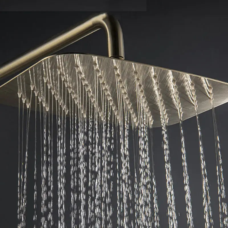 The bathroom boasts a sophisticated shower setup, showcasing the Mike Jake Solid Brass Shower Mixer with Bathtub Faucet and a handheld shower wand against a dark gray wall. Water cascades from the brass rain shower head, creating droplets that glisten in the light. A sleek sink faucet adds to the modern aesthetic, while light gray cabinets provide an elegant backdrop.