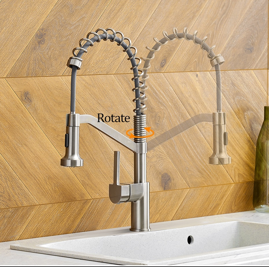 A modern kitchen faucet from allfixture, the Wanfan™ Pull Out Single Handle Swivel Kitchen Faucet, is pictured with a brushed stainless steel finish. It features a flexible coil spring spout and a pull-down spray head. Shown in two positions to illustrate its rotation capability, highlighted by an orange arrow, the faucet's quality is comparable to that of high-end bathroom fixtures.