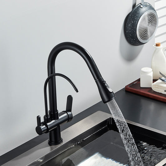 A Rozin Brass Kitchen Faucet With Filtered Water Tap, featuring dual handles, is installed over a stainless steel sink with water flowing from the spout. A pan and bottles are also visible on the nearby countertop.