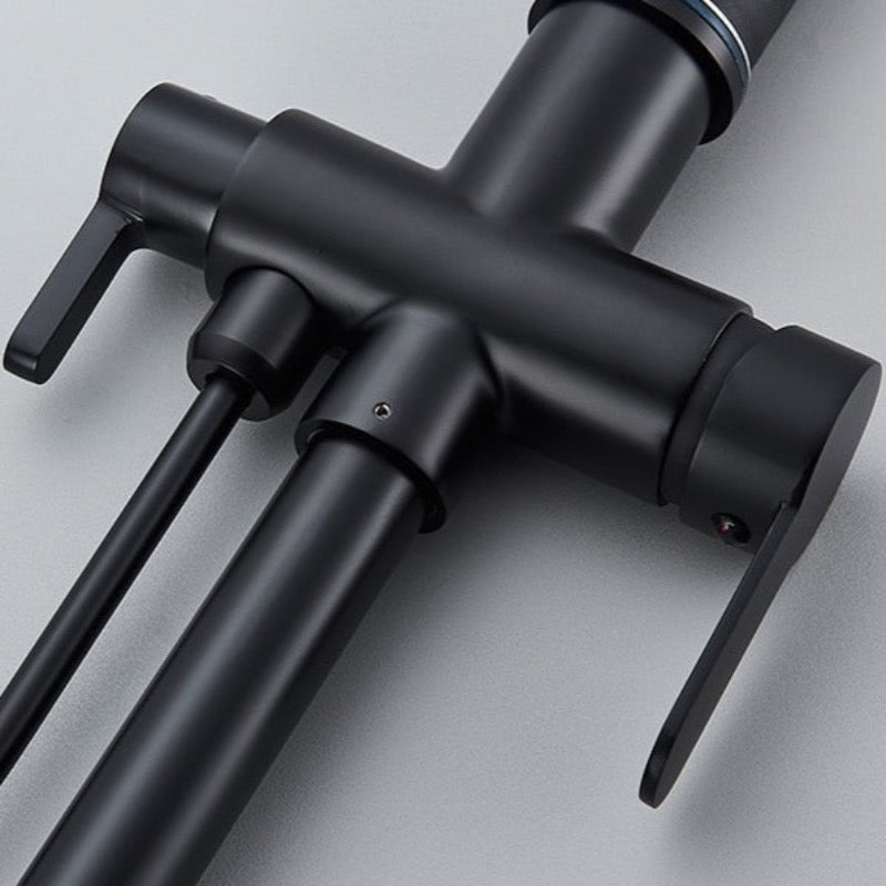A person is turning on the Rozin Touch Sensor Brass Kitchen Faucet With Filtered Water Tap, which features a sleek, modern black design and a curved spout. Water flows smoothly into the sink below while kitchen items like a pan, soap dispenser, and bottles are visible on the counter in the background. This versatile faucet could easily complement any bathroom sink or shower setup.