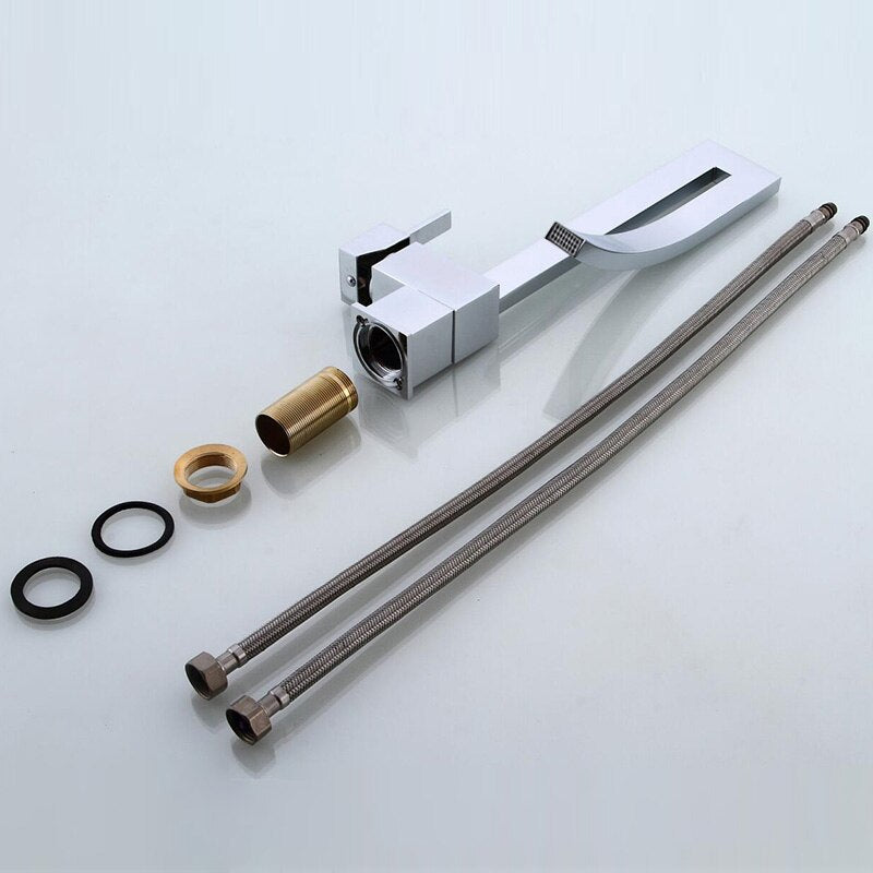 A modern, sleek Deck Mounted Brass Bathroom Basin Faucet from Bacala, featuring a curved design in black, is dispensing water into a white sink. In the background, there's a vase with dried flowers and a toothbrush holder containing a black and white toothbrush. The wall appears to be tiled in a dark color, echoing the elegance of a premium shower head.