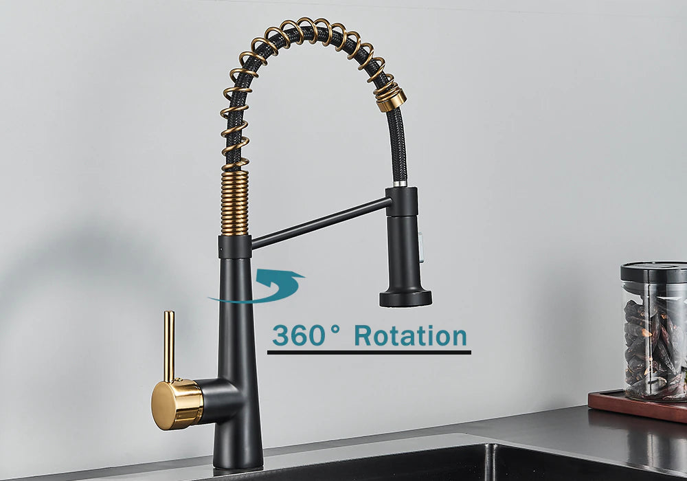 A modern Rozin Deck Mounted Pull Down Sprayer Kitchen Sink Faucet, featuring a sleek black finish with gold accents, is installed over a stainless steel sink. The faucet boasts a curved, flexible spring spout with a convenient pull-down sprayer. In the background, jars and a white panel on the wall enhance the sleek design.