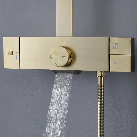 A Wall Mounted Shower Faucet With Handheld Shower Sprayer by Mike Jake is mounted on a light gray wall. It showcases a square overhead shower head, a handheld shower wand attached to a stainless steel hose, and boasts a minimalist design with a rectangular control valve. A bottle is visible on a shelf to the left of the sleek shower faucet.