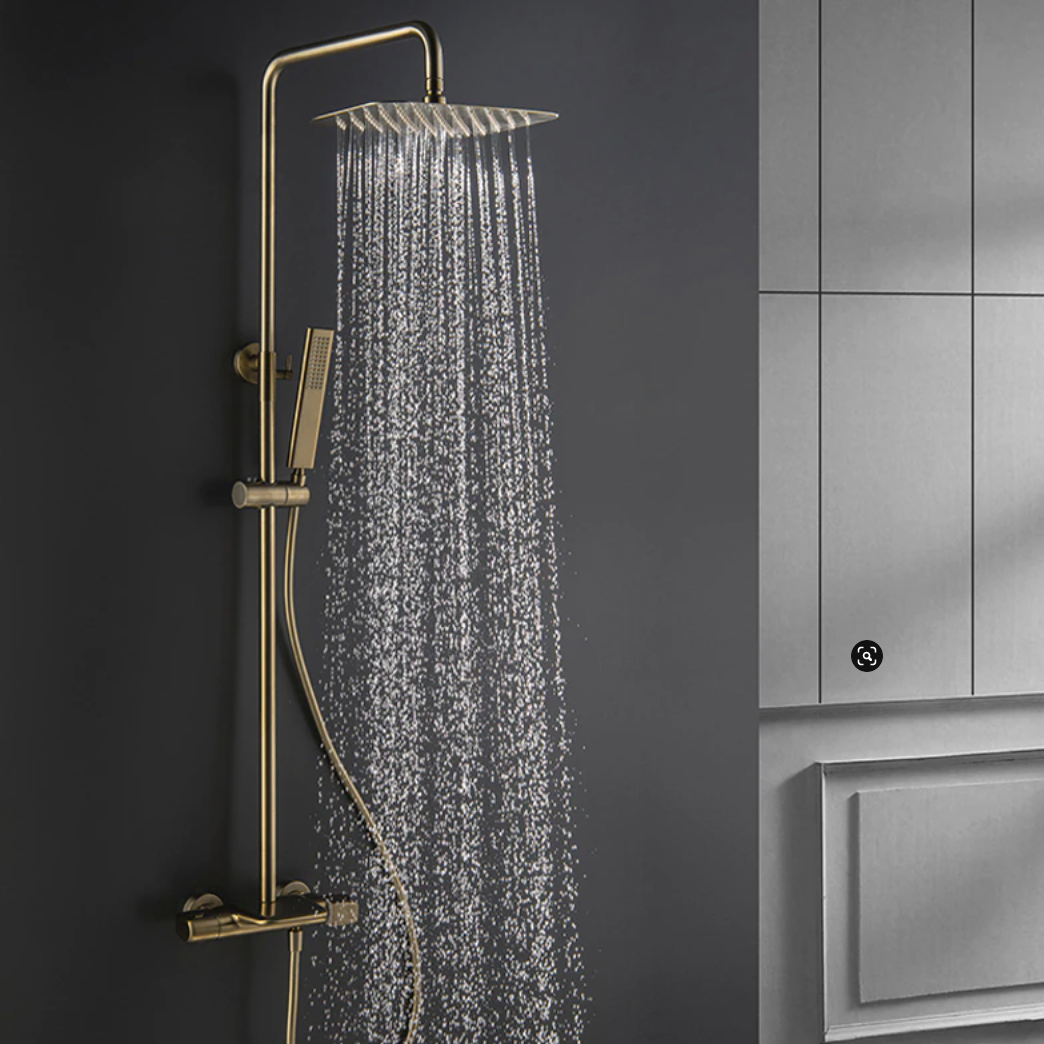 The bathroom boasts a sophisticated shower setup, showcasing the Mike Jake Solid Brass Shower Mixer with Bathtub Faucet and a handheld shower wand against a dark gray wall. Water cascades from the brass rain shower head, creating droplets that glisten in the light. A sleek sink faucet adds to the modern aesthetic, while light gray cabinets provide an elegant backdrop.
