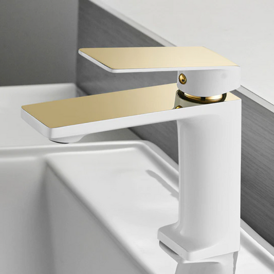 The Wanfan Single-Handle Solid Brass Bathroom Basin Faucet features a sleek white base and flat brushed gold handle, mounted on a white sink with a gray and white wall backdrop for a modern look.