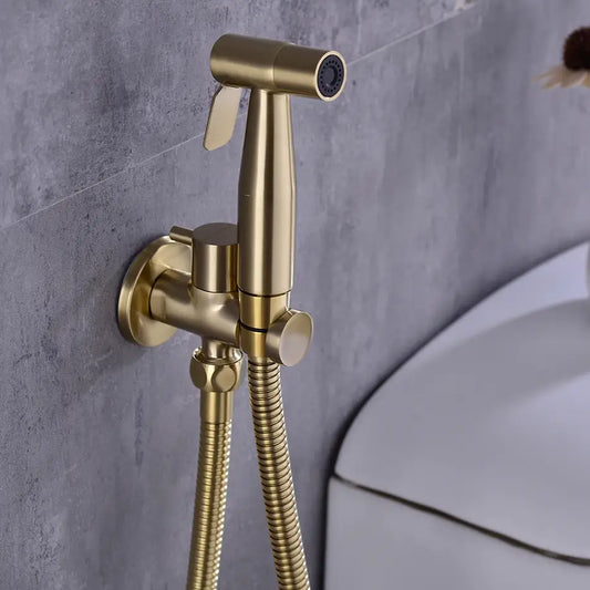 The AllFixture Wasser™ Solid Brass handheld Toilet Sprayer Faucet in gold is wall-mounted beside a white toilet, showcased against gray tiles.