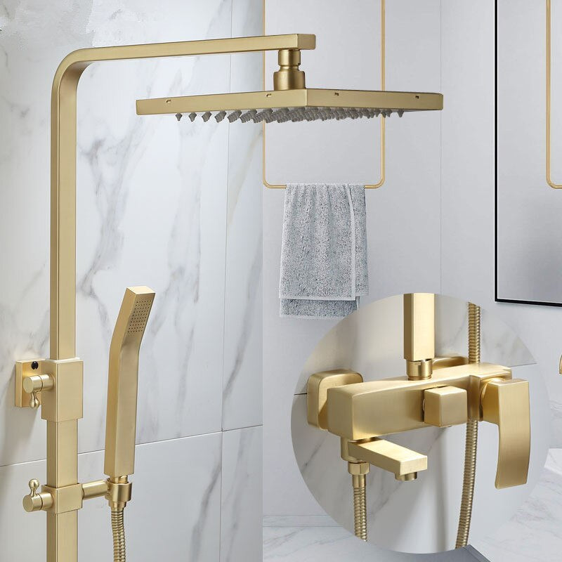 A modern bathroom featuring the Wasser™ Brushed Gold Shower System from Morsale.com, which includes a square overhead rain showerhead and a matching handheld showerhead. A detailed inset highlights the sleek gold faucet and lever controls of the stylish bathroom sink faucet. The background shows marble-style wall tiles and a hanging towel.