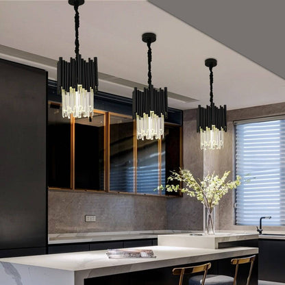 A modern kitchen featuring a marble island, illuminated by the Vigo Kitchen Island Light Fixture from Morsale.com. This premium stainless steel light fixture boasts three black and gold pendants. The gray cabinetry perfectly complements the vase with branches on the countertop, while large windows with blinds elevate the sleek and contemporary ambiance.