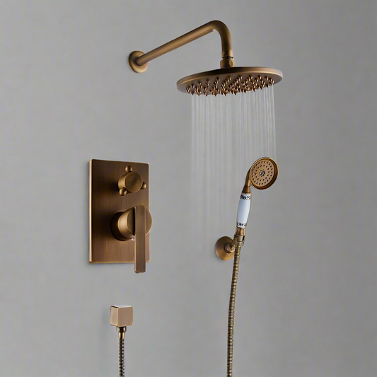 The Rozin Antique Brass Shower System With Handheld Shower includes a round rain shower head, flexible hose hand shower, and wall-mounted control knobs, all showcased against a plain gray wall.