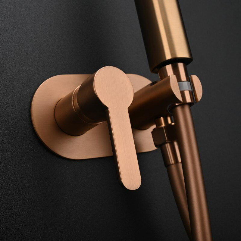 A sleek, modern Mike Jake Wall Mounted Brushed Gold Toilet Sprayer Bidet Faucet against a black wall. The fixture includes a handheld sprayer with two buttons and a temperature control lever. This contemporary design complements the sprayer faucet, ensuring both style and functionality in your bathroom.