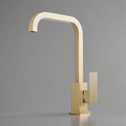 The Tiqui™ Solid Brass Single Handle Kitchen Faucet by Tiqui features a modern gold finish, a square base, and a sleek single lever handle, showcased against a simple gray background.