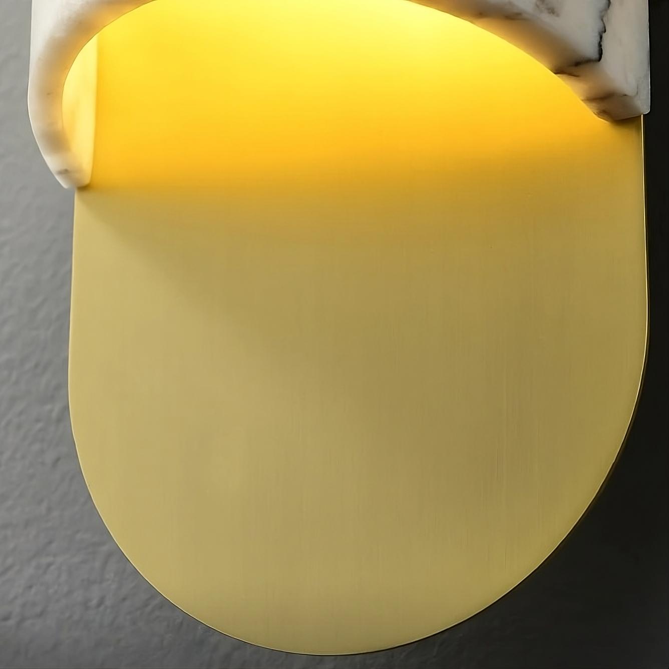 A modern, wall-mounted light fixture is shown, featuring a half-circle design. The top half is crafted from natural marble, and the lower half boasts a smooth, matte gold finish. With energy-efficient LED lighting, it emits a warm glow that softly illuminates the wall behind it. This Natural Marble Wall Sconce Light Fixture by Morsale.com perfectly combines elegance and function for any contemporary space.
