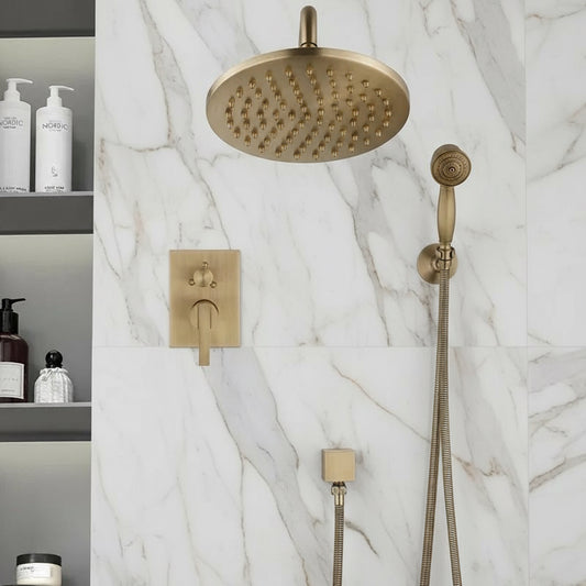 The Heritage Antique Brass Shower System with Handheld Shower from Morsale.com features solid brass gold fixtures, a round rainfall shower head, and control lever on a white marble wall. Shelves with bottles and toiletries are visible to the left.