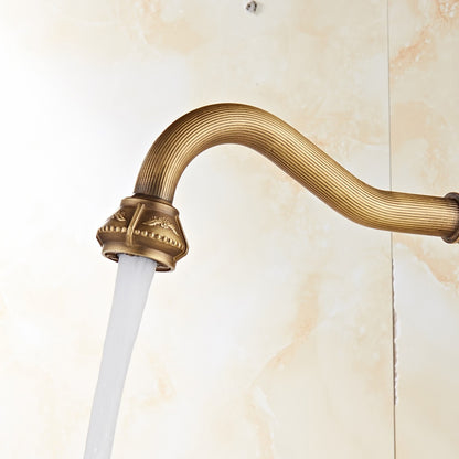 A Miho Single Handle Antique Bronze Faucet with intricate vintage-style designs is mounted on a marble countertop. The background features a beige marble-patterned wall, and a yellow soap bar is placed next to the faucet.