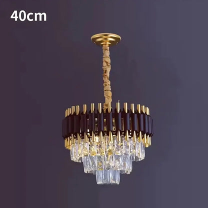 Introducing the Morsale.com Verano Crystal Chandelier: a luxurious and modern centerpiece with a 40 cm diameter that exudes chic sophistication. Featuring a gold and dark brown frame adorned with tiered, rectangular crystal prisms, it elegantly reflects light to create an exquisite ambiance. The chandelier is suspended from a gold chain wrapped in beige fabric for added refinement.