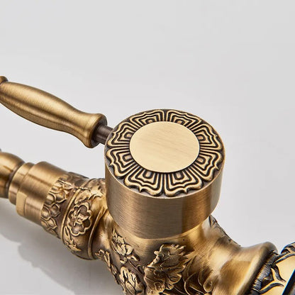 An Antique Brass Single Handle Faucet by Rozin, with its intricate carvings, streams water into a modern stainless steel sink against a textured white tile backsplash.