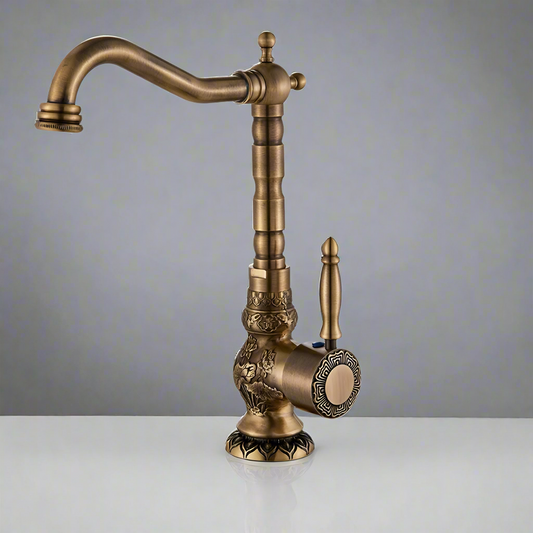 The Rozin Antique Brass Single Handle Faucet features ornate detailing, a curved spout, and a single lever handle, showcased against a plain gray background on a white surface.