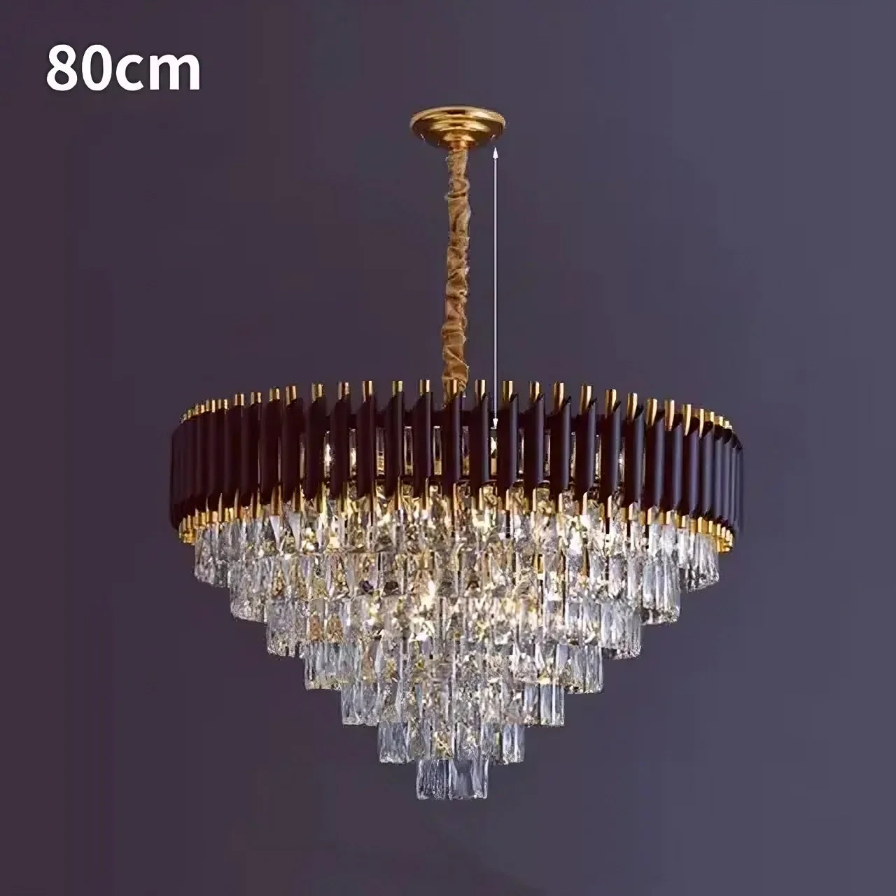 The Verano Crystal Chandelier from Morsale.com, boasting an 80cm diameter, elegantly hangs from the ceiling. It features a concentric brown and gold frame adorned with cascading rows of high-quality crystal-like rectangular prisms, creating sophisticated decor against a dark background.