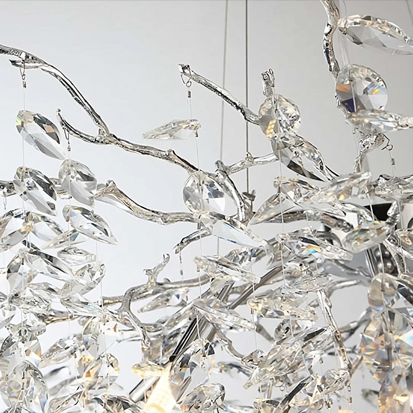 A close-up of the Albero Collection Crystal Ceiling Light Fixture by Morsale.com showcases its intricate design with numerous clear crystal-like pendants hanging from silver branches. The adjustable hanging wire ensures perfect placement, while the dimmable LED bulbs reflect light to create a sparkling, elegant effect against a blurred background.