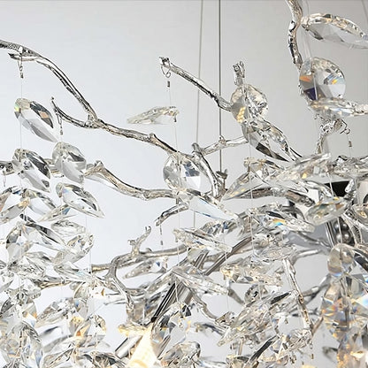 A close-up of the Albero Collection Crystal Ceiling Light Fixture by Morsale.com showcases its intricate design with numerous clear crystal-like pendants hanging from silver branches. The adjustable hanging wire ensures perfect placement, while the dimmable LED bulbs reflect light to create a sparkling, elegant effect against a blurred background.