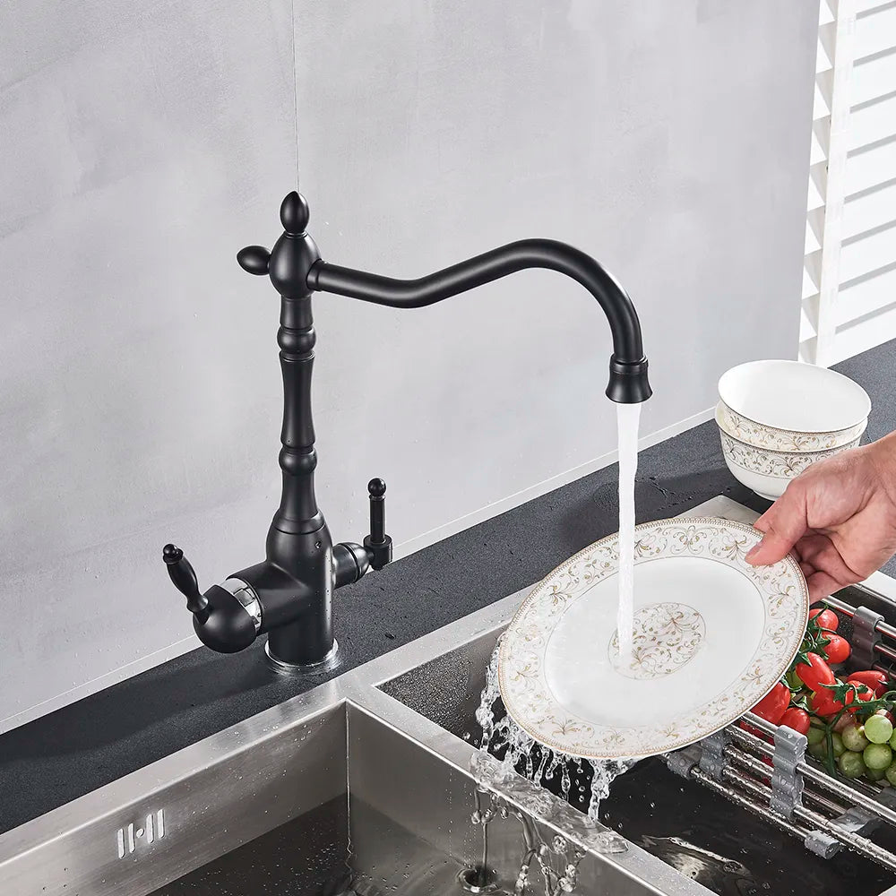 A Uythner Contemporary Kitchen Faucet With Filtered Water Tap is mounted over a stainless steel sink. The faucet is turned on, with water flowing from the spout. Behind the sink are a white container and a variety of fresh vegetables, including tomatoes.