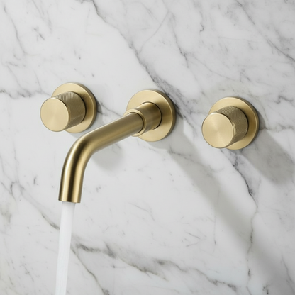 The Tiqui Windsor Wall Mounted Bathroom Faucet in brushed gold showcases two round handles and a curved spout, set against a light gray background.