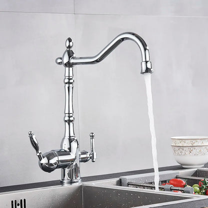 A modern Uythner chrome kitchen faucet with a filtered water tap releases a steady stream of water into a stainless steel sink filled with various vegetables. A ceramic bowl with an intricate pattern sits on the countertop, and the background is a minimalist gray wall.